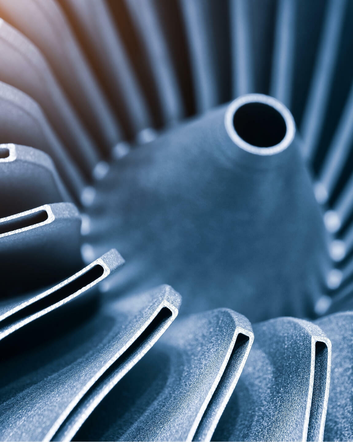 Close-up of a metallic turbine or motor housing with radial fins and a central opening.